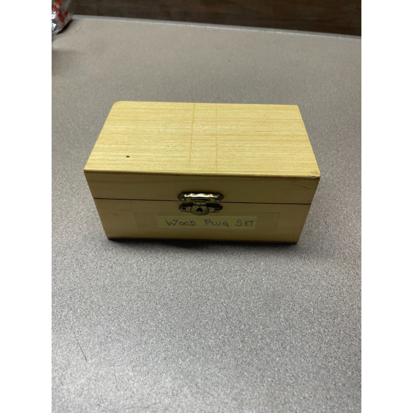 Wooden box labeled 'Wood Plug Set' on a gray surface