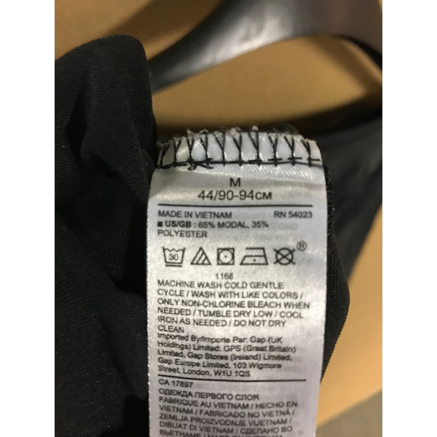 Close-up of a clothing label on a black garment with a beige background.