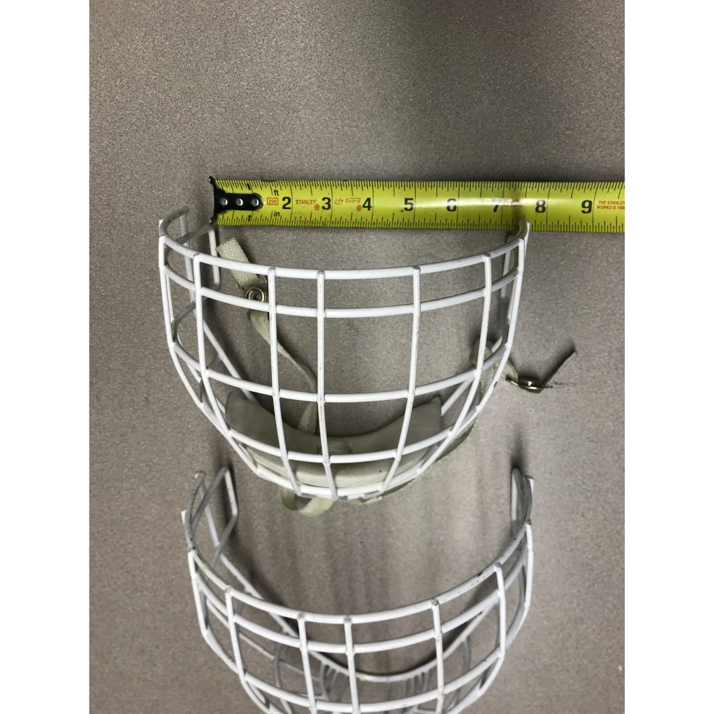 Two Hockey Cage Masks White Metal 7.5 inch (one with chin pad) front view ruler indicating 7.5 inch across top