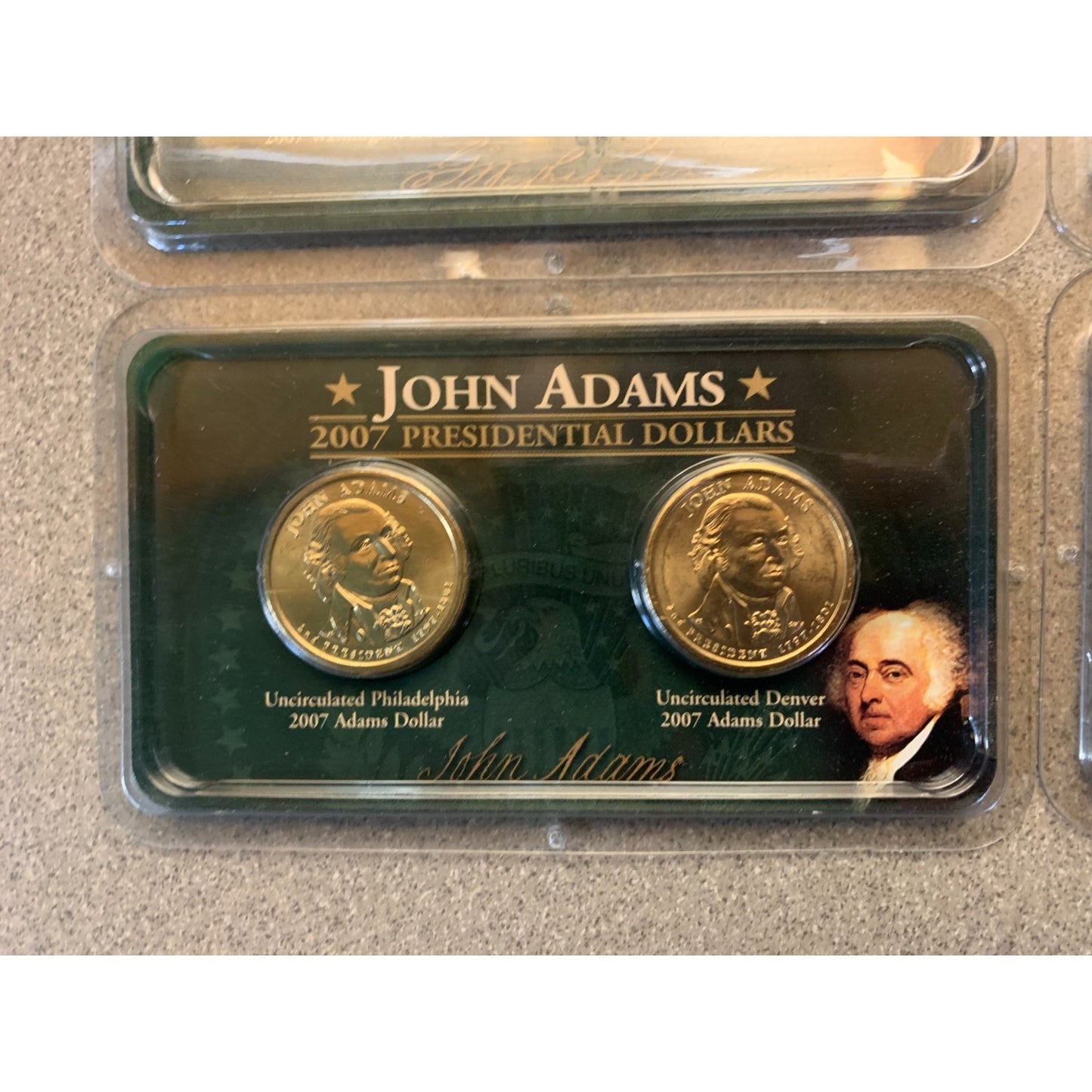 John Adams presidential dollar coins in a display case on a beige surface