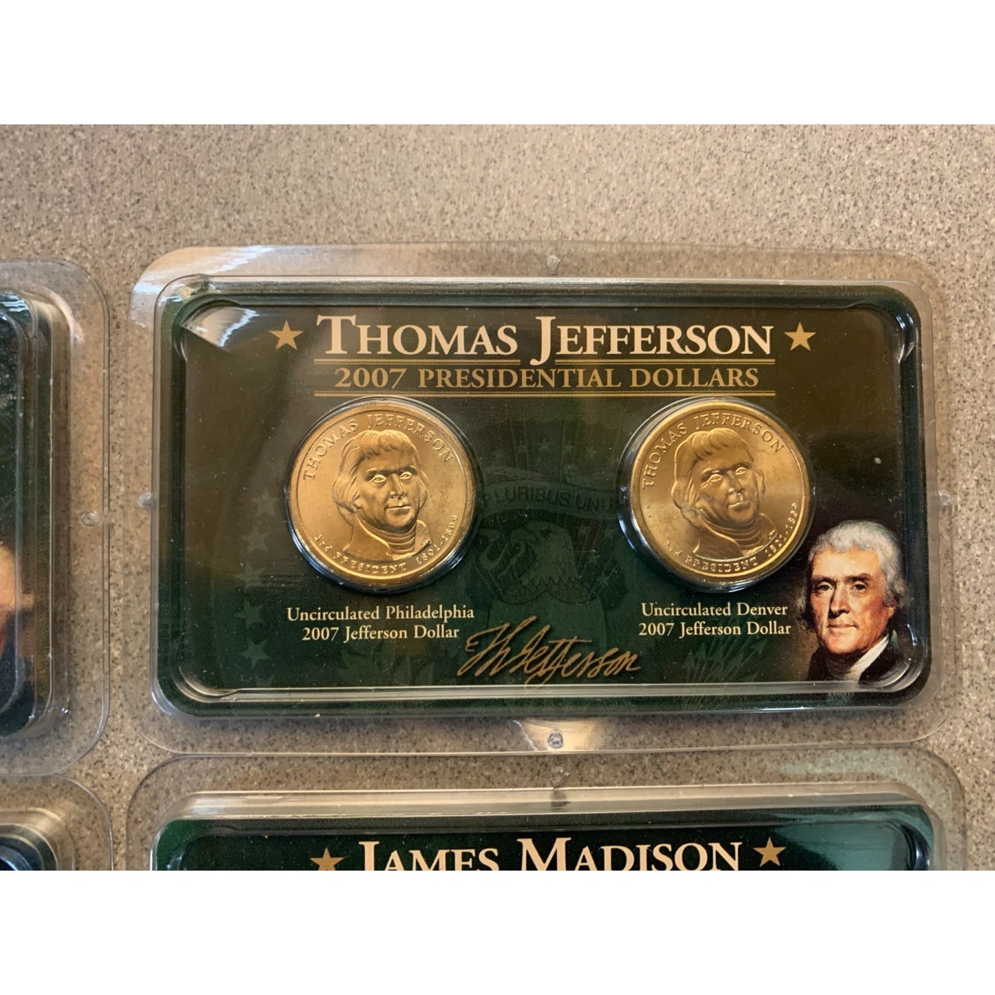 Two gold coins in a display case with Thomas Jefferson's portrait and name on a beige background.