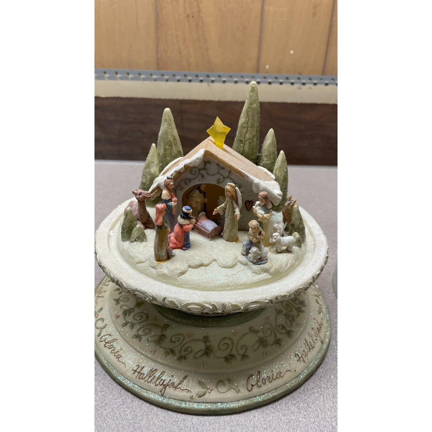 Decorative nativity scene on a stand with trees and a star on a neutral background