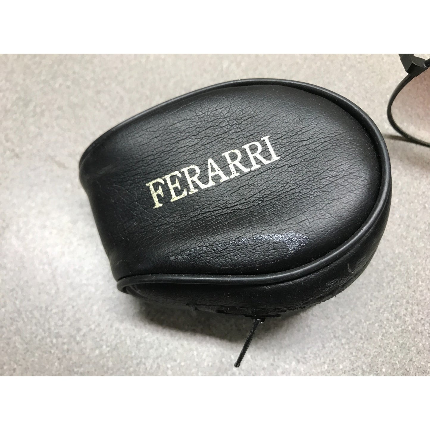 Black Ferrari earbud case on a light gray surface