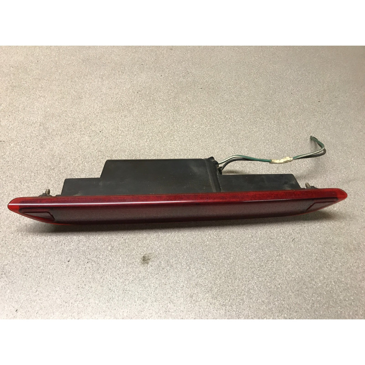 A used car taillight assembly with a red lens and a black backing housing, shown on a neutral gray textured surface. 2005-2010 Honda Odyssey OEM High Mount Third Brake Light