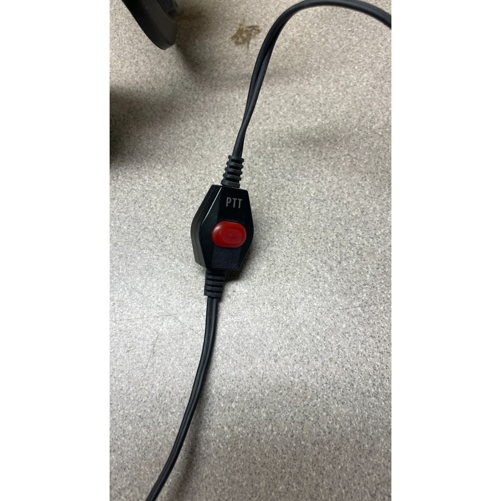 Black PTT switch with red button on a gray surface