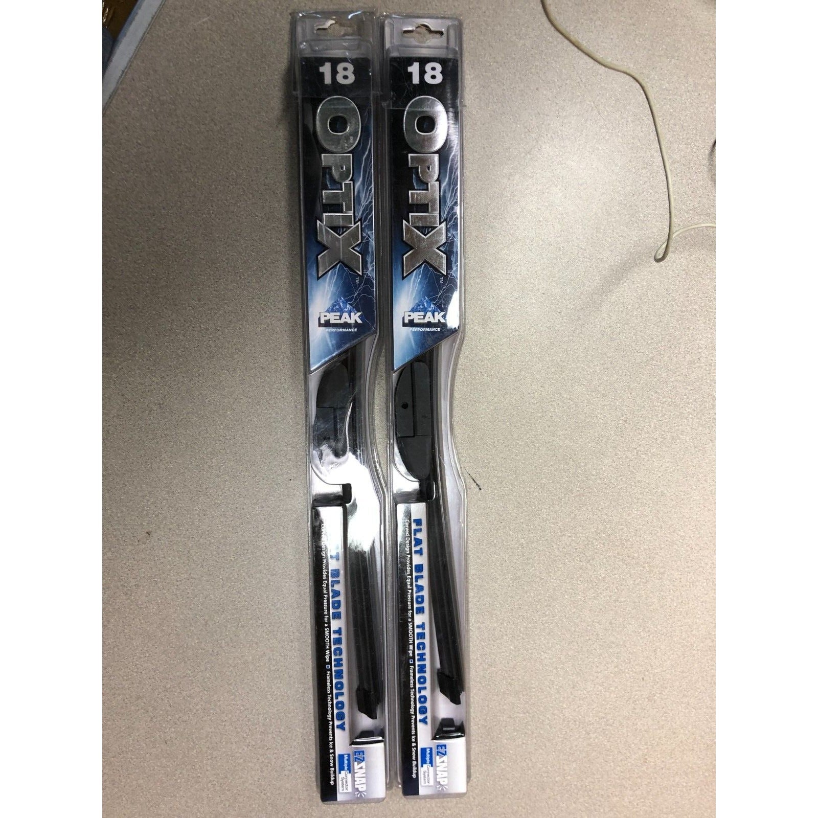 Two packages of Optix Peak windshield wiper blades on a beige surface.