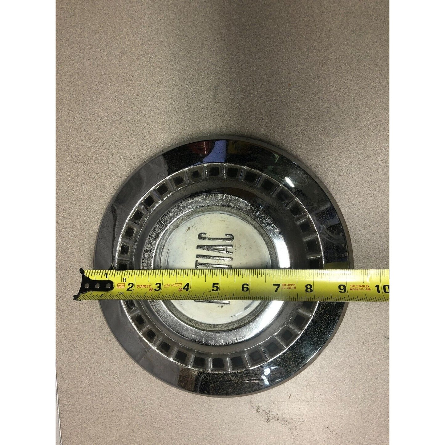 1966 Pontiac Chrome OEM Wheel Center Cap front view with measuring tape approximately 9 inch diameter