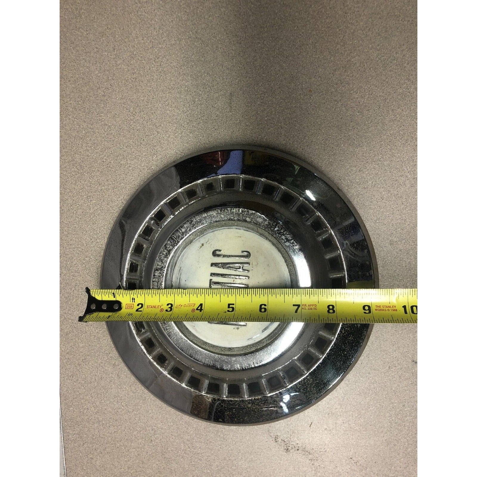 1966 Pontiac Chrome OEM Wheel Center Cap front view with measuring tape approximately 9 inch diameter