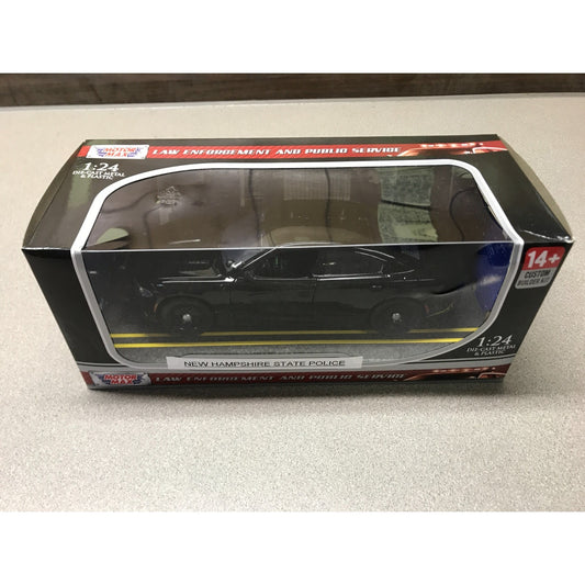 A 1:24 scale diecast model car of the New Hampshire State Police in a black classic coupe, displayed inside its original retail packaging on a light gray surface. front of package displaying vehicle
