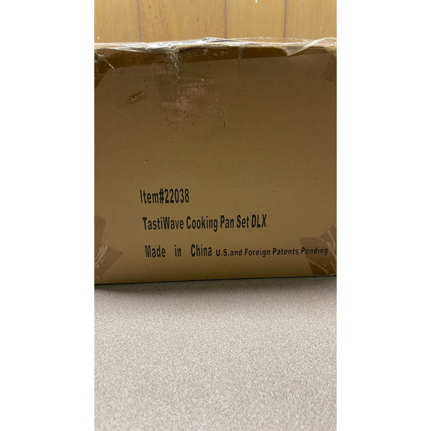 Cardboard box with TastiWave Cooking Pan Set DLX branding on a neutral background