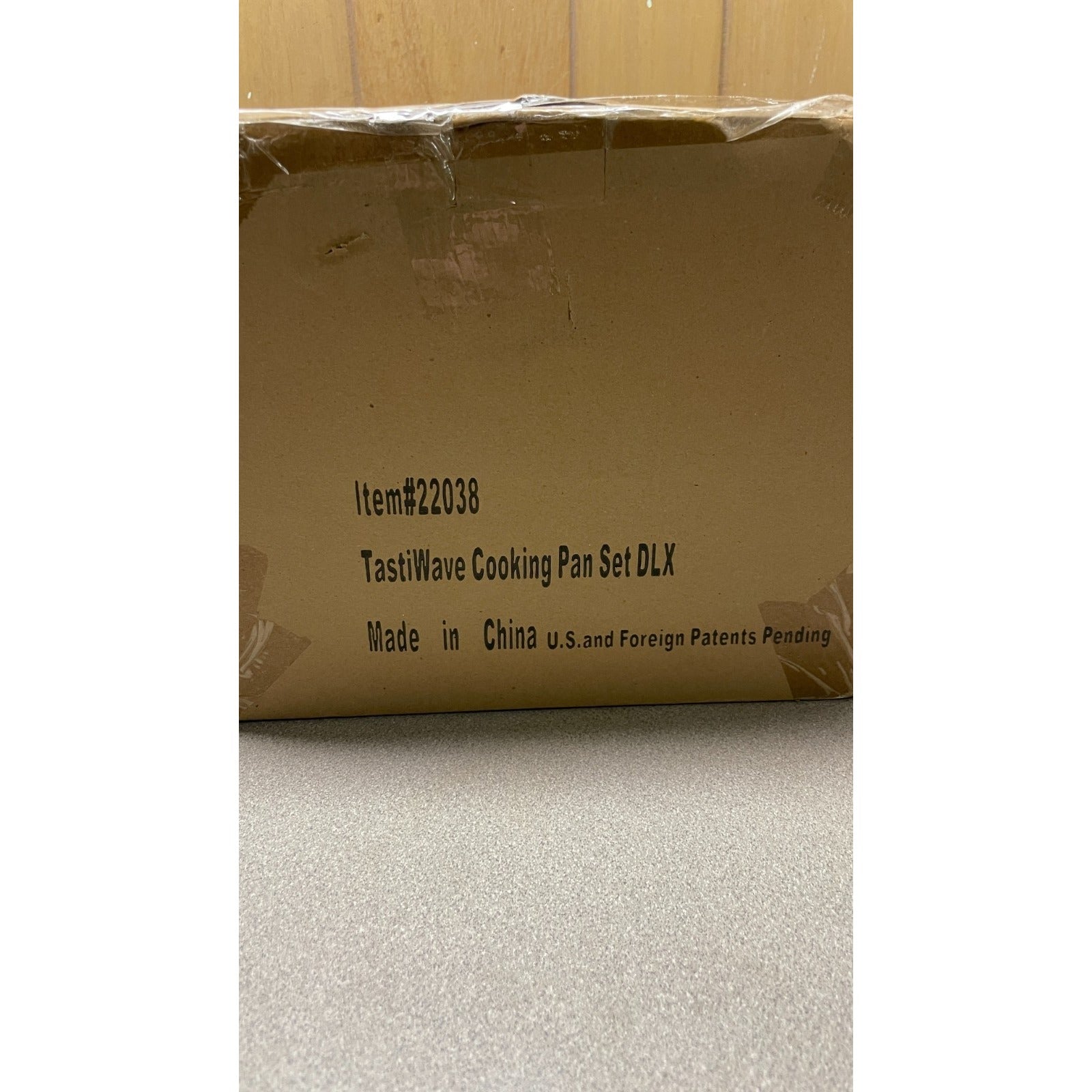 Cardboard box with TastiWave Cooking Pan Set DLX branding on a neutral background