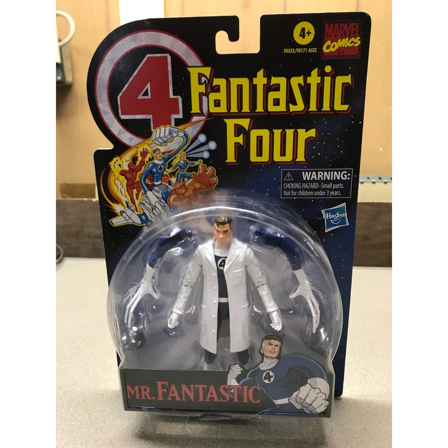Hasbro Marvel Comics 4 Fantastic Four Mr. Fantastic action figure in original blister packaging, featuring the character in a white lab coat with black and gray accents, set against a dark cardback with colorful comic-style artwork.