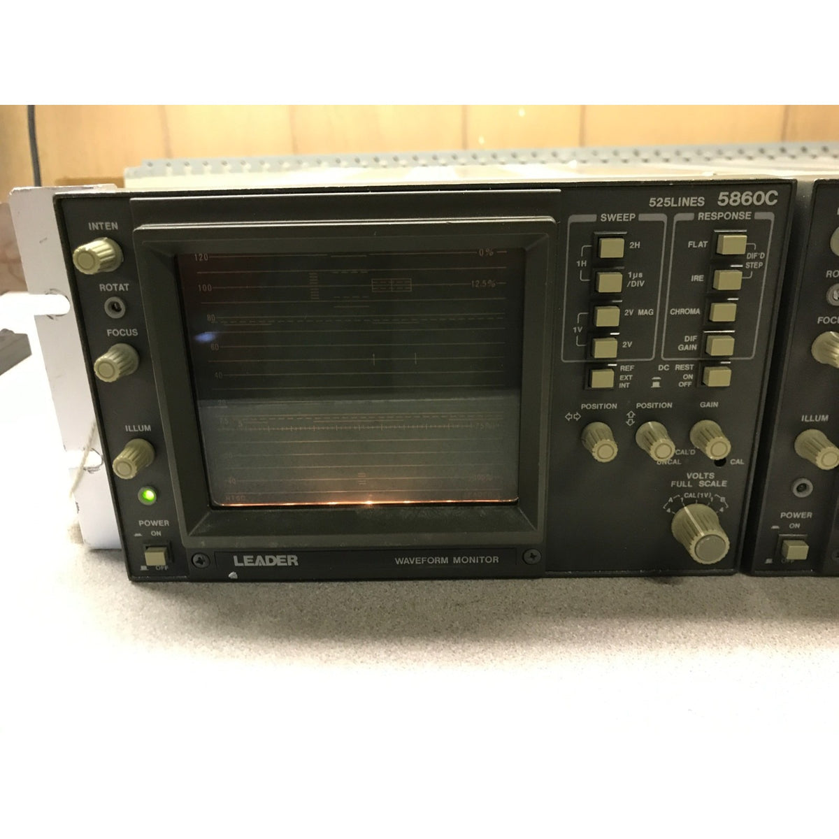 A vintage LEADER 5860C 9-band signal generator and waveform monitor, featuring a black front panel with beige knobs and a dark screen, photographed on a light surface. Powered on