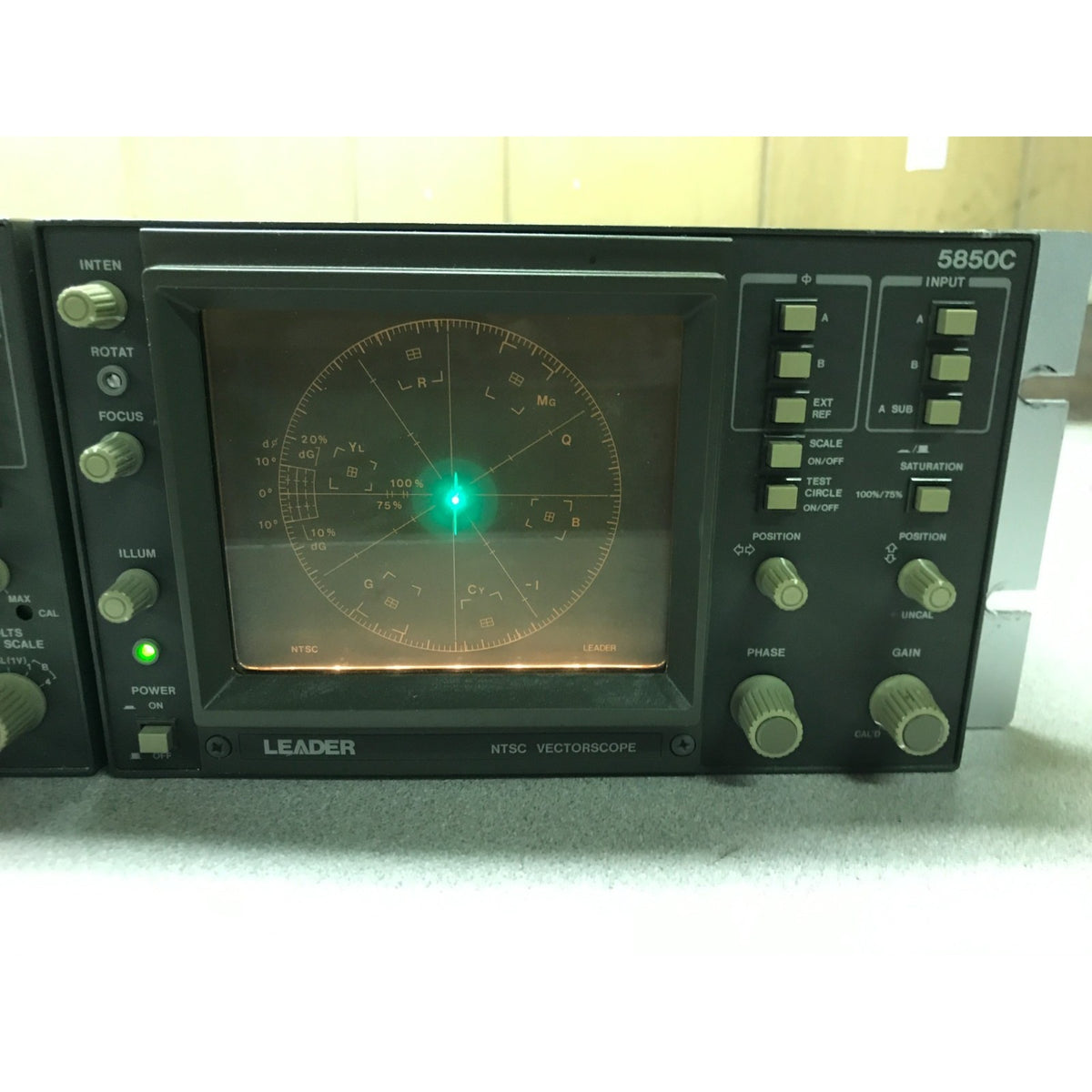 A LEADER 5850C NTSC vectorcope electronic testing device with a black front panel, illuminated display screen, and multiple control knobs and switches. Powered on