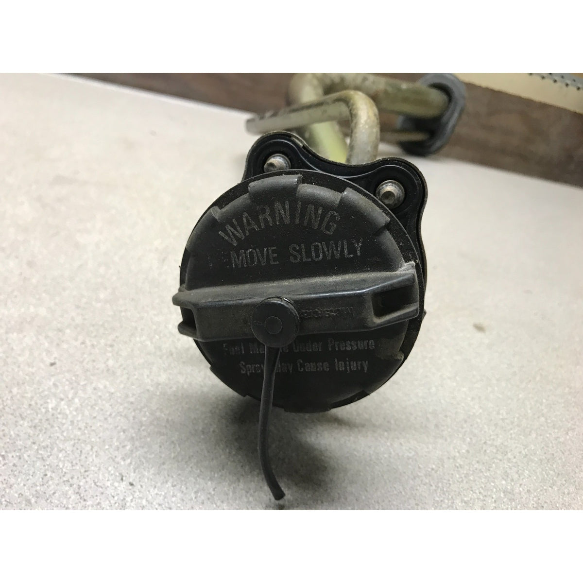 A black automotive fuel pump assembly with a warning label and a metal hose, photographed on a light gray surface. 1993-1997 Honda Civic Del Sol OEM Gas Filler Neck