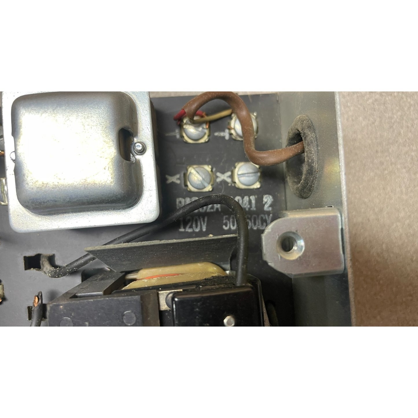 Close-up of an electronic component with wiring and labels on a metallic surface.