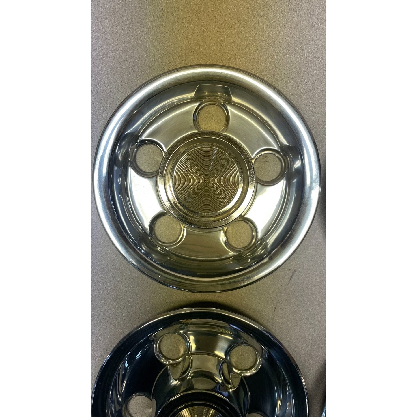 Two metallic hubcaps on a beige background