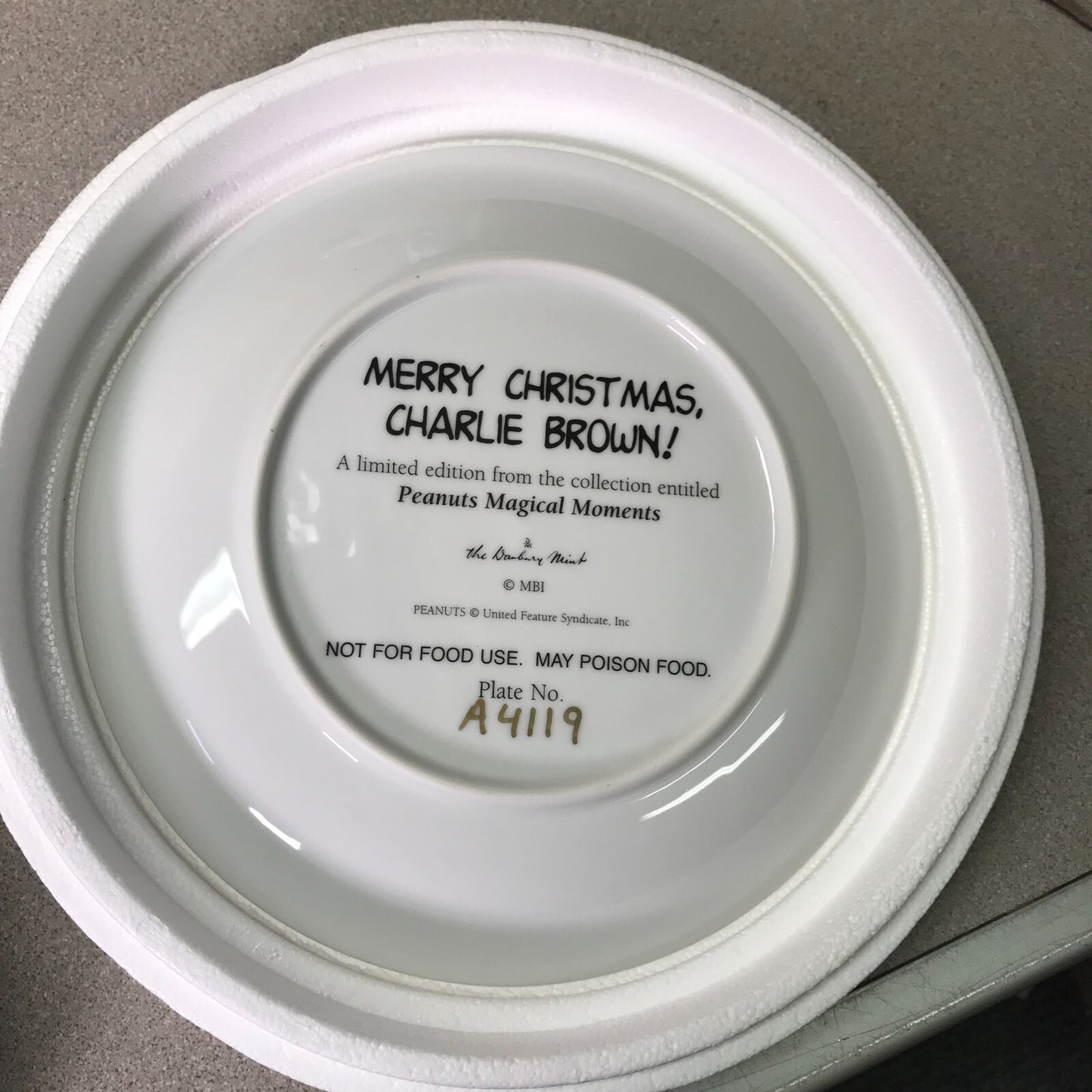 Back of a white plate with black text on a gray surface. title and serial number