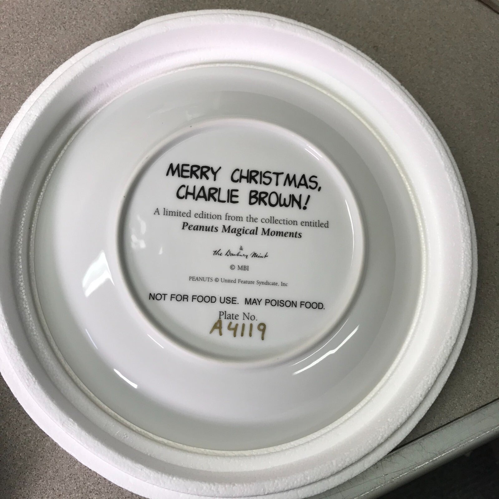 Back of a white plate with black text on a gray surface. title and serial number