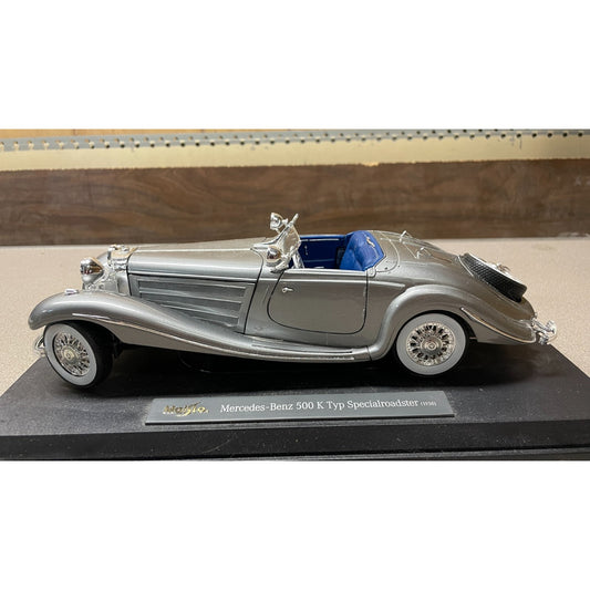 Maisto Silver 1936 Mercedes-Benz 500 K Typ Specialroadster 1:18 Scale Diecast Model drivers side view on display platform