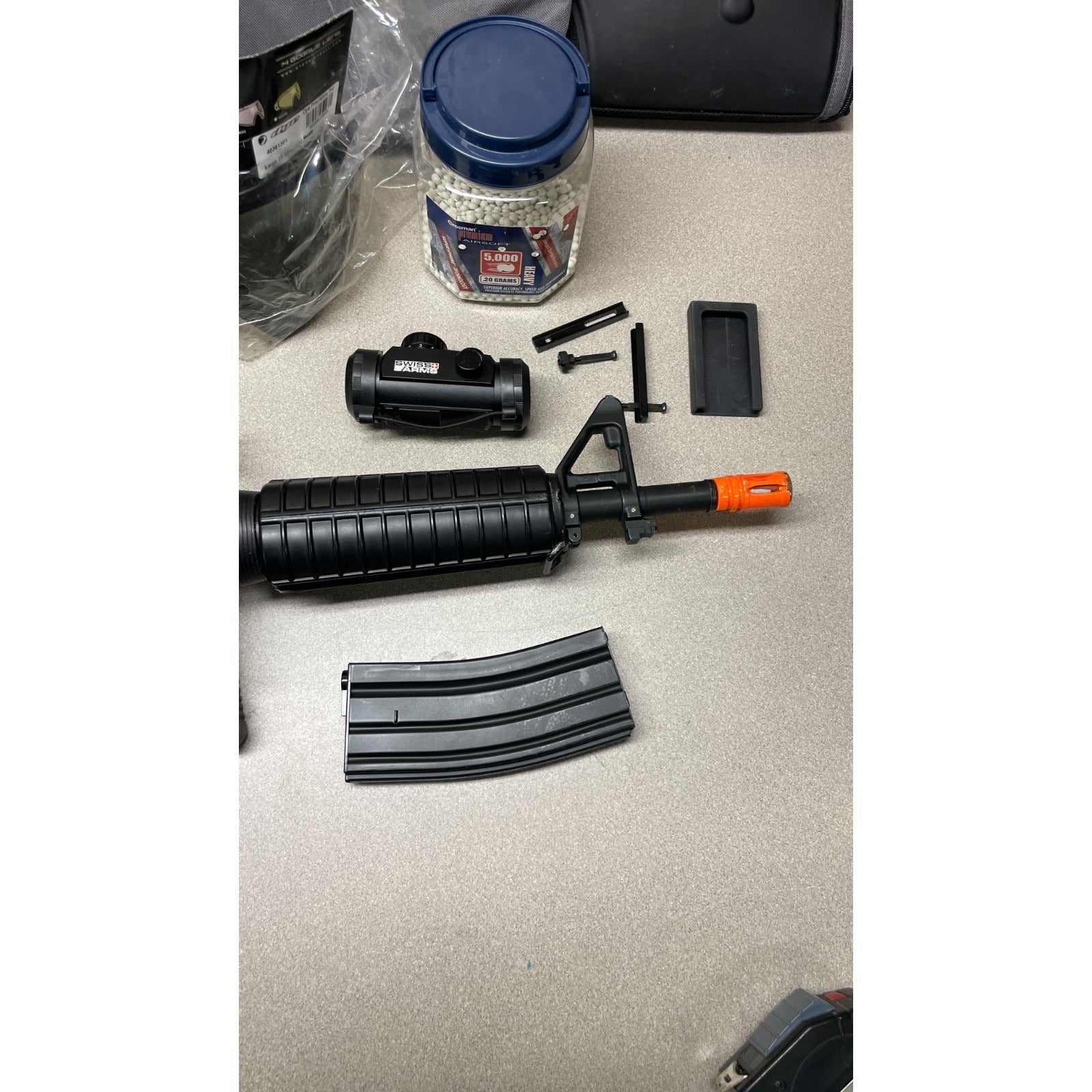 DPMS Panther Arms U050810381 M4 Style Airsoft Gun Lot UNTESTED, Accessories and Bag Included. Swiss Arms Sight, DYE i4 Goggle Lens, Crosman .20 Grams Airsoft closeup of gun nozzle and accessories