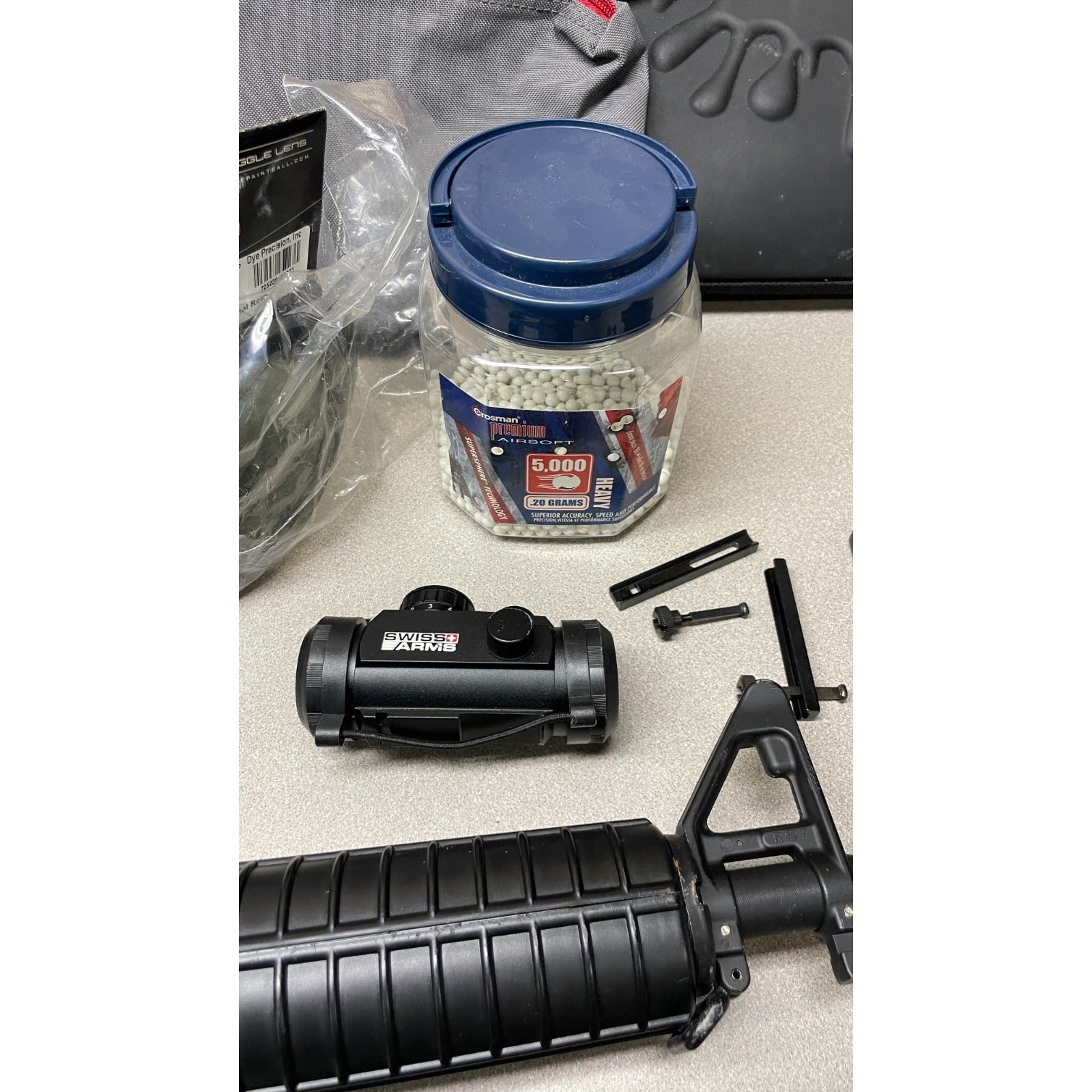 DPMS Panther Arms U050810381 M4 Style Airsoft Gun Lot UNTESTED, Accessories and Bag Included. Swiss Arms Sight, DYE i4 Goggle Lens, Crosman .20 Grams Airsoft closeup of accessories