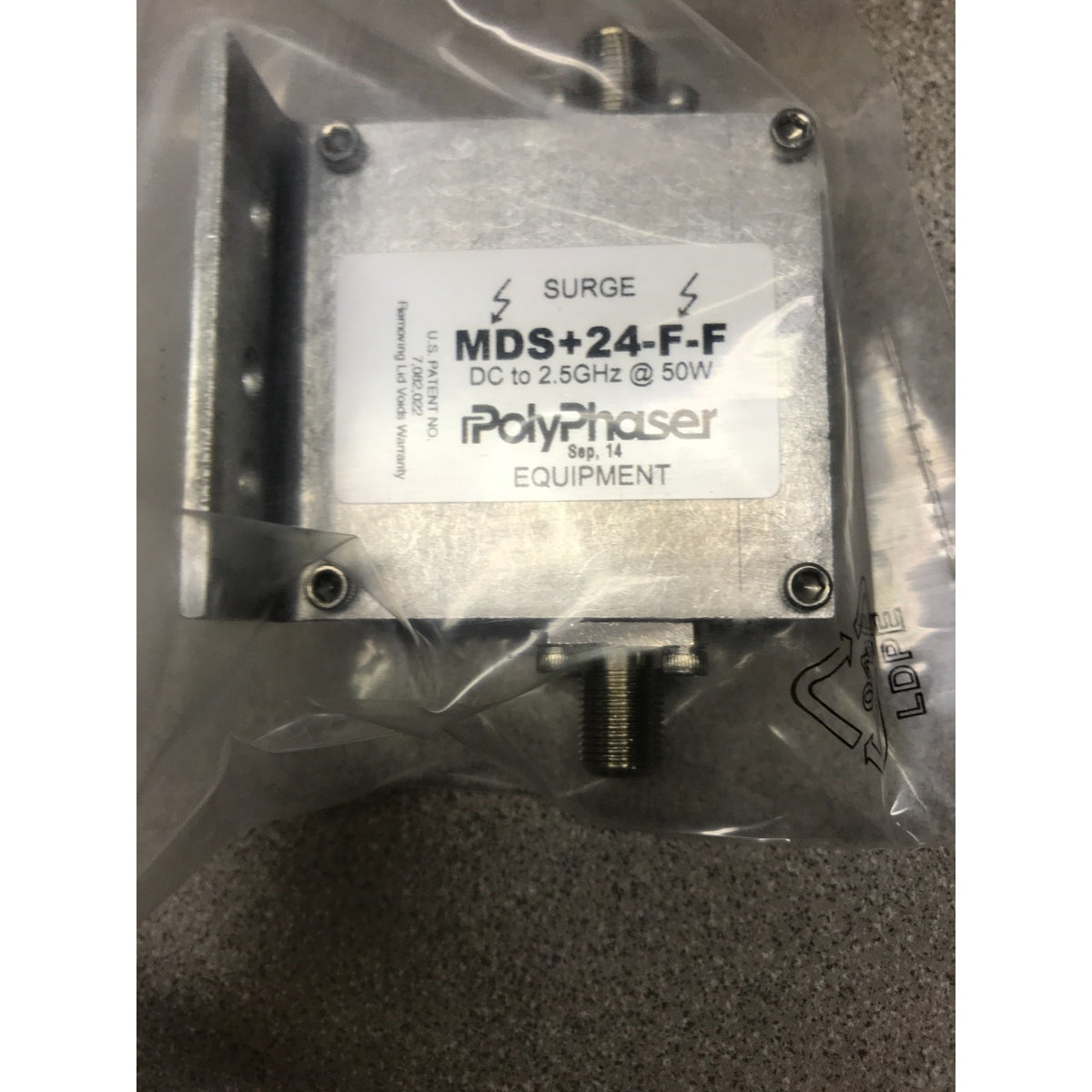 A PolyPhaser MDS+24-F.F electronic component in its clear plastic packaging, featuring a silver metal housing with a white label.