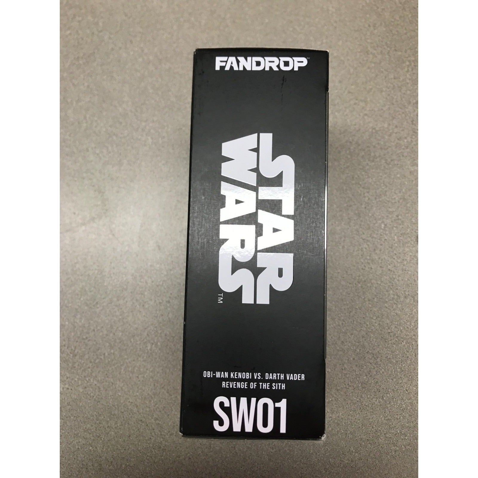 A black product box for a Fandrop Star Wars SW01 Obi-Wan Kenobi vs. Darth Vader Revenge of the Sith collectible, photographed on a textured gray surface.