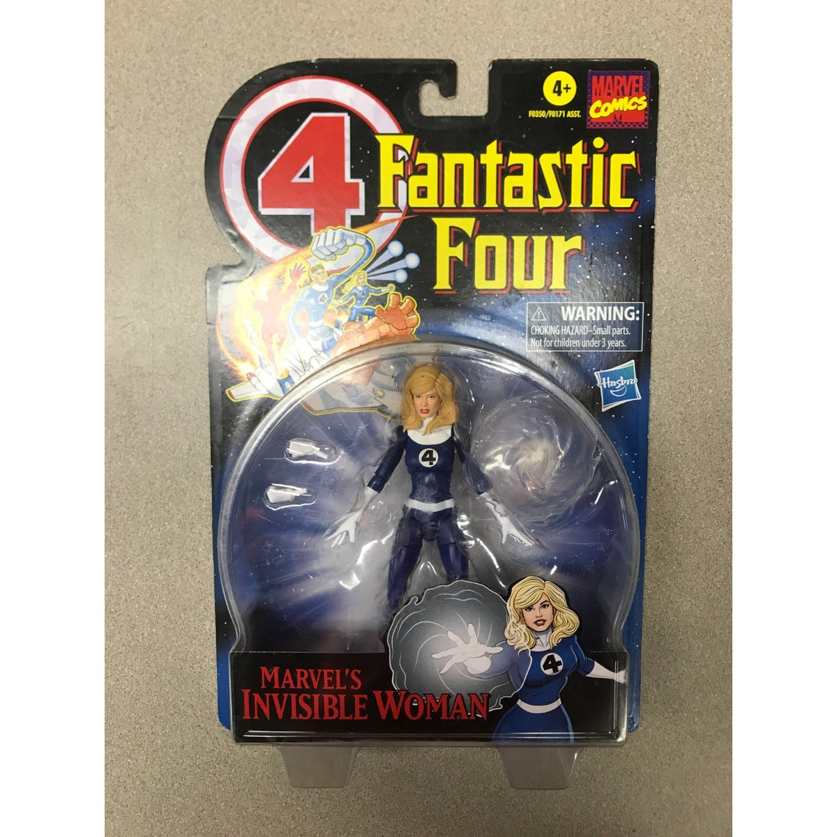 Hasbro Marvel Comics 4 Fantastic Four action figure of Marvel's Invisible Woman in original blister card packaging, shown against a neutral beige background.
