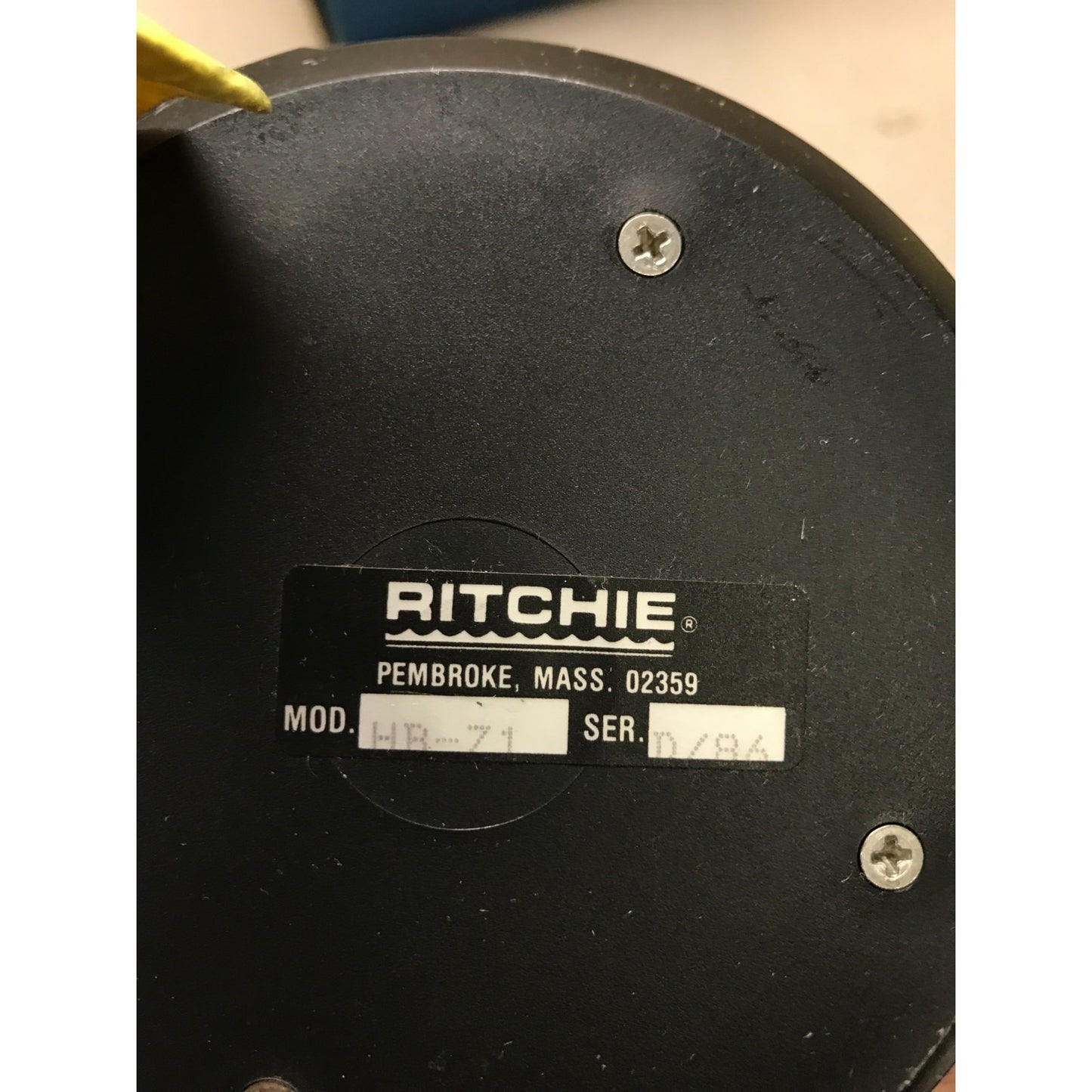 Close-up of a Ritchie brand product with a label on a black background with model and serial number