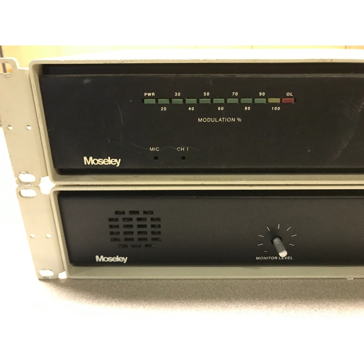 Two stacked Moseley audio signal processors or amplifiers in a beige rack, showing front control panels with dials, switches, and indicator lights.