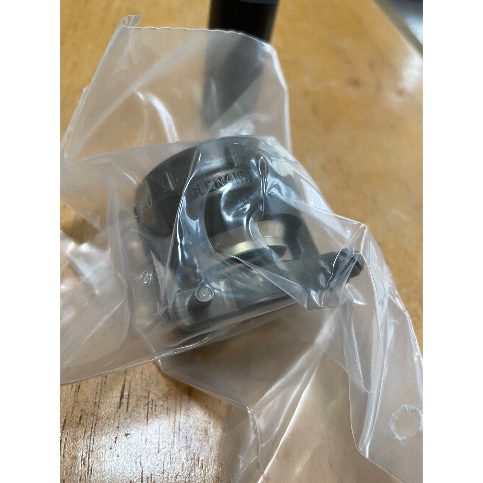 Metal component in clear plastic packaging on a wooden surface