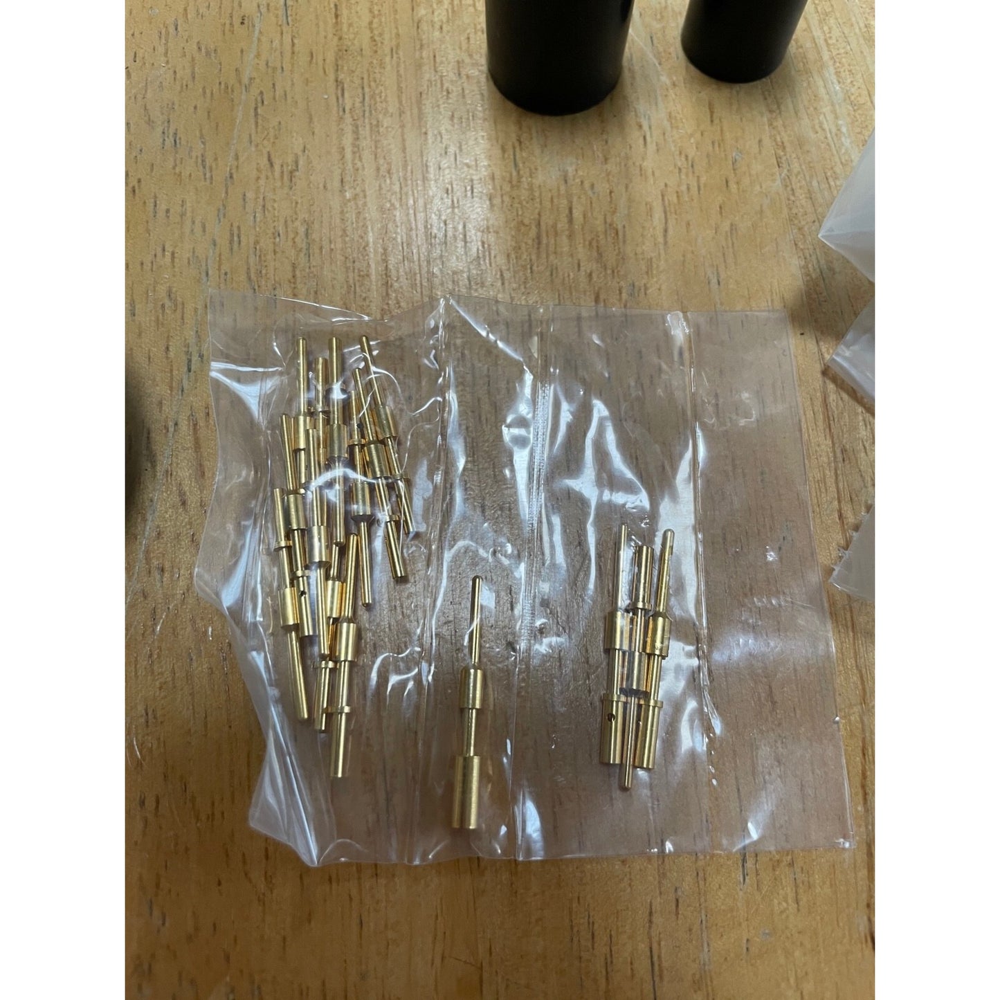 Gold cylindrical objects in a clear plastic bag on a wooden surface