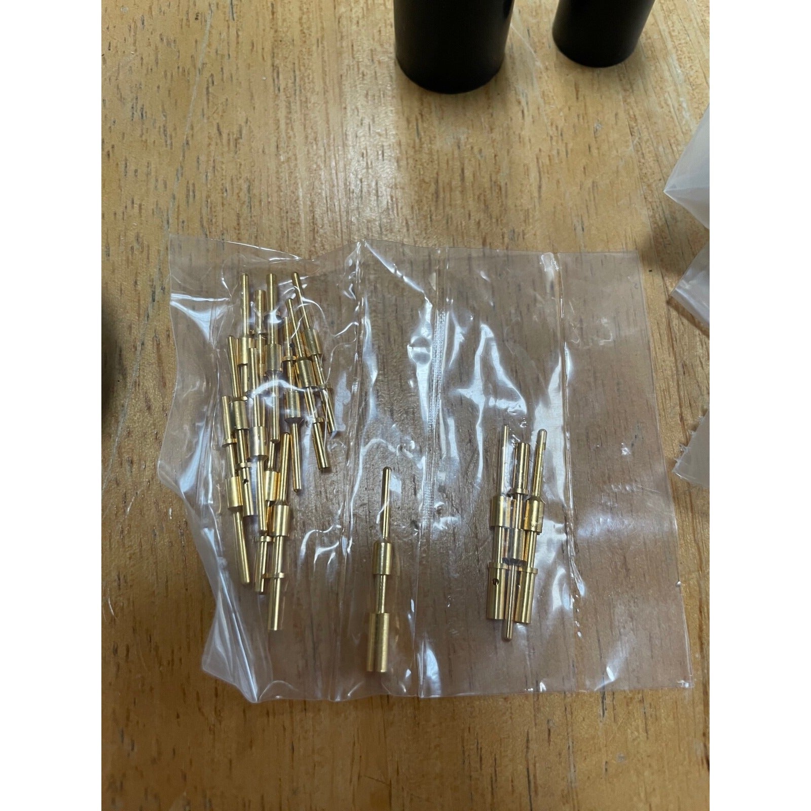 Gold cylindrical objects in a clear plastic bag on a wooden surface