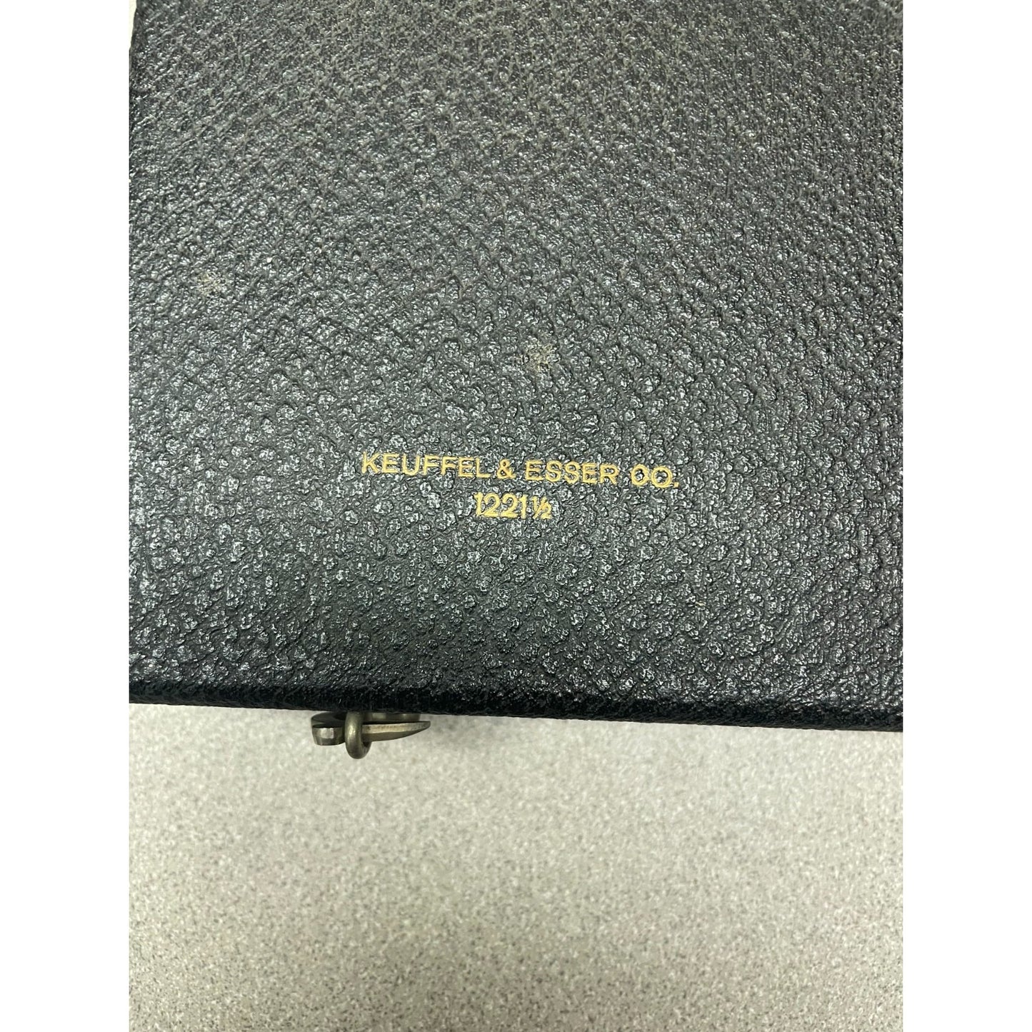 Close-up of a textured black leather case with gold foil embossed branding reading 'KEUFFEL & ESSEN DO. 12013' on a light gray background.