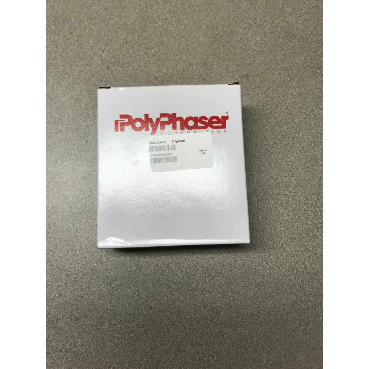A white PolyPhaser industrial product box with red branding, placed on a textured gray surface.