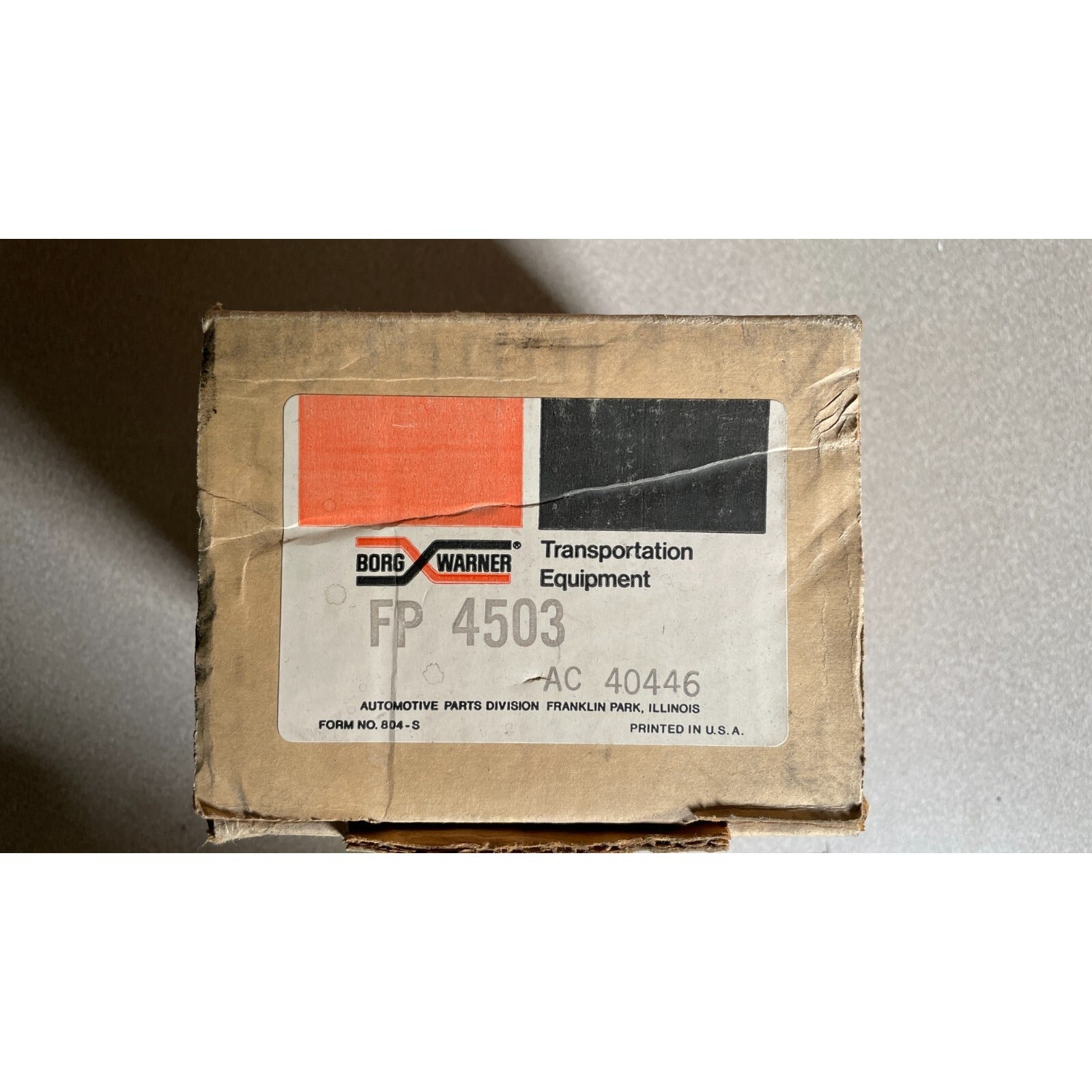 Cardboard box with a Borg Warner label on a gray background