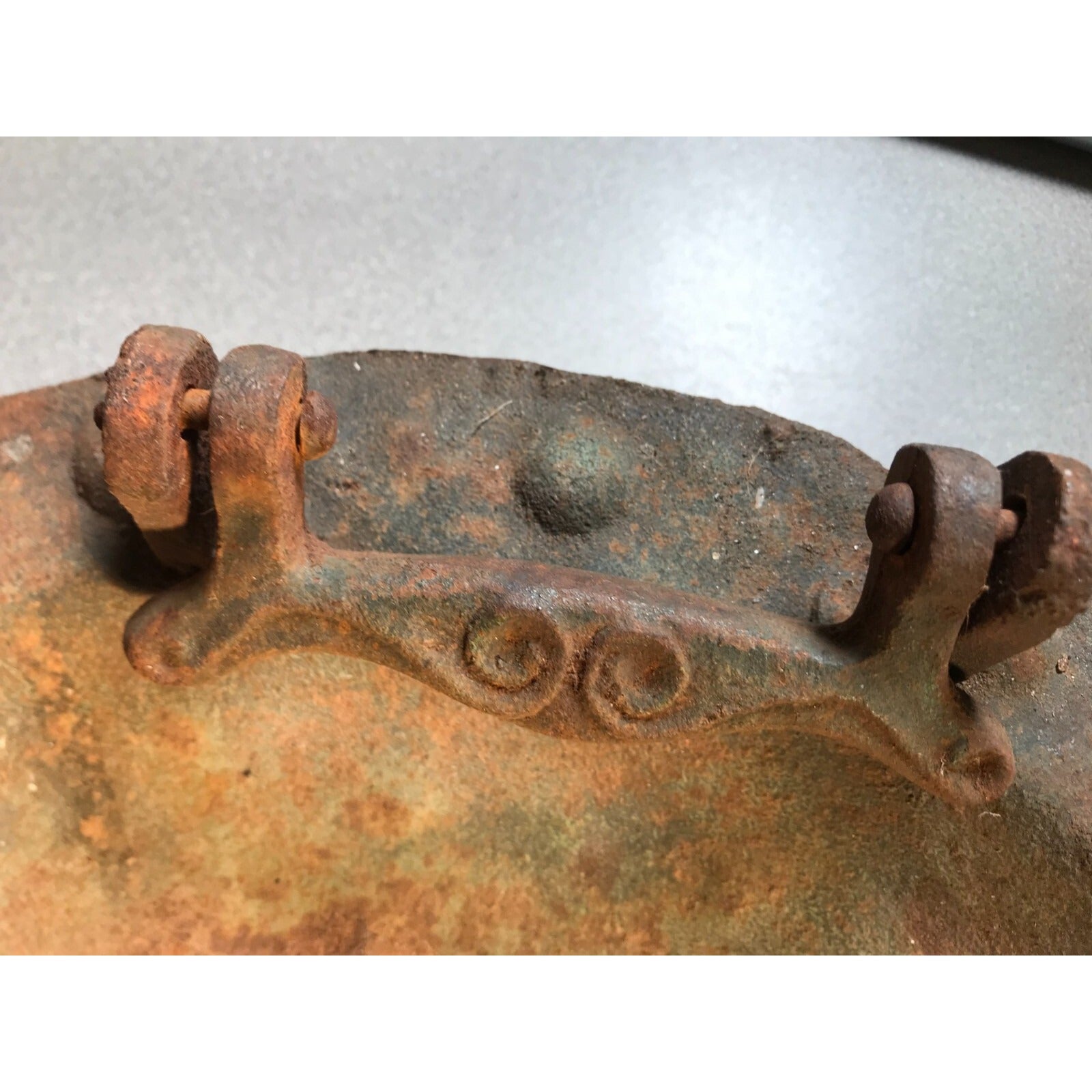 Antique Solid Iron Fire Cooking Bowl closeup of handle shows rust and scroll detail