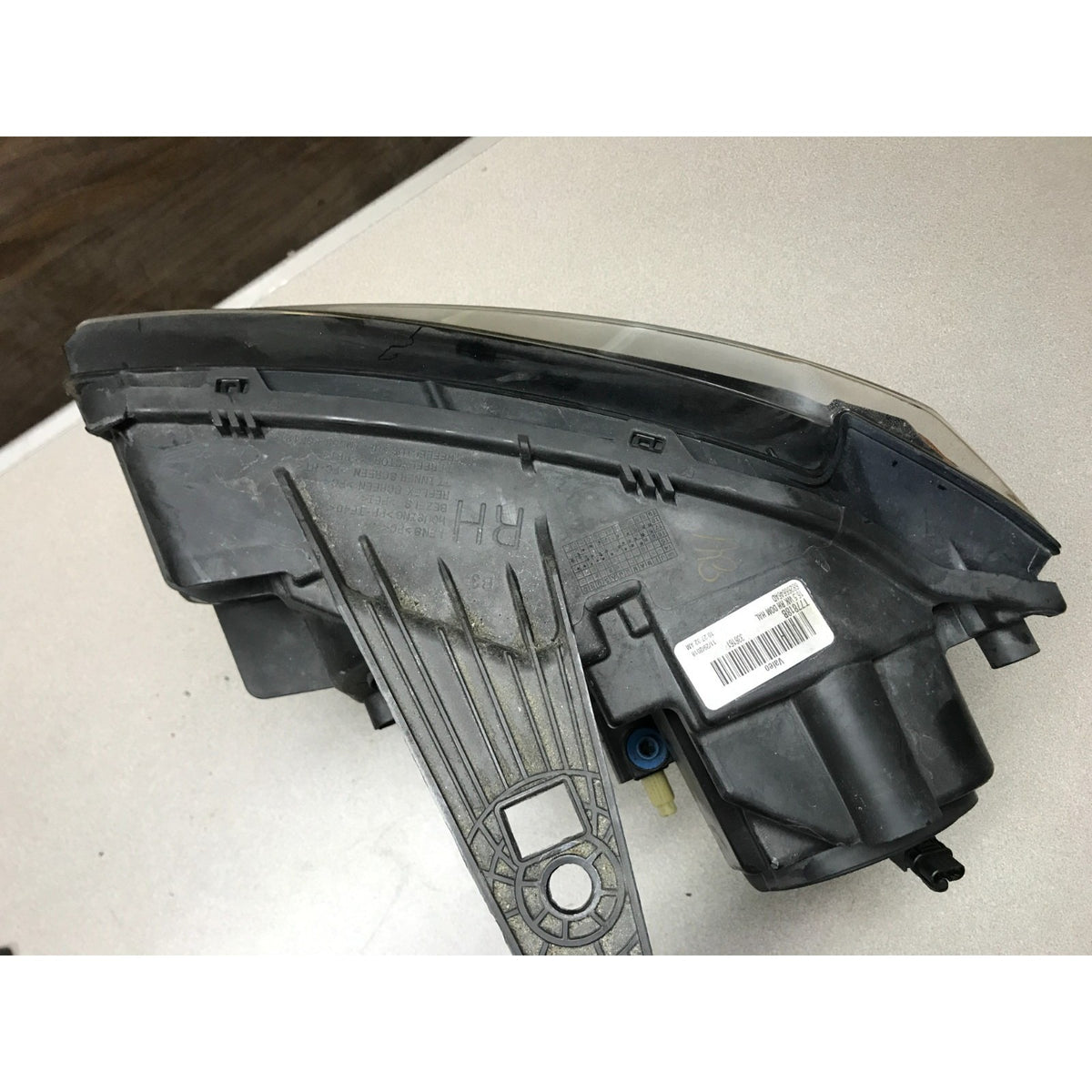 A used black plastic automotive headlight assembly with a clear lens, photographed on a light-colored surface. 2019 Jeep Grand Cherokee Altitude Front Right RH Valeo OEM Headlight Lens
