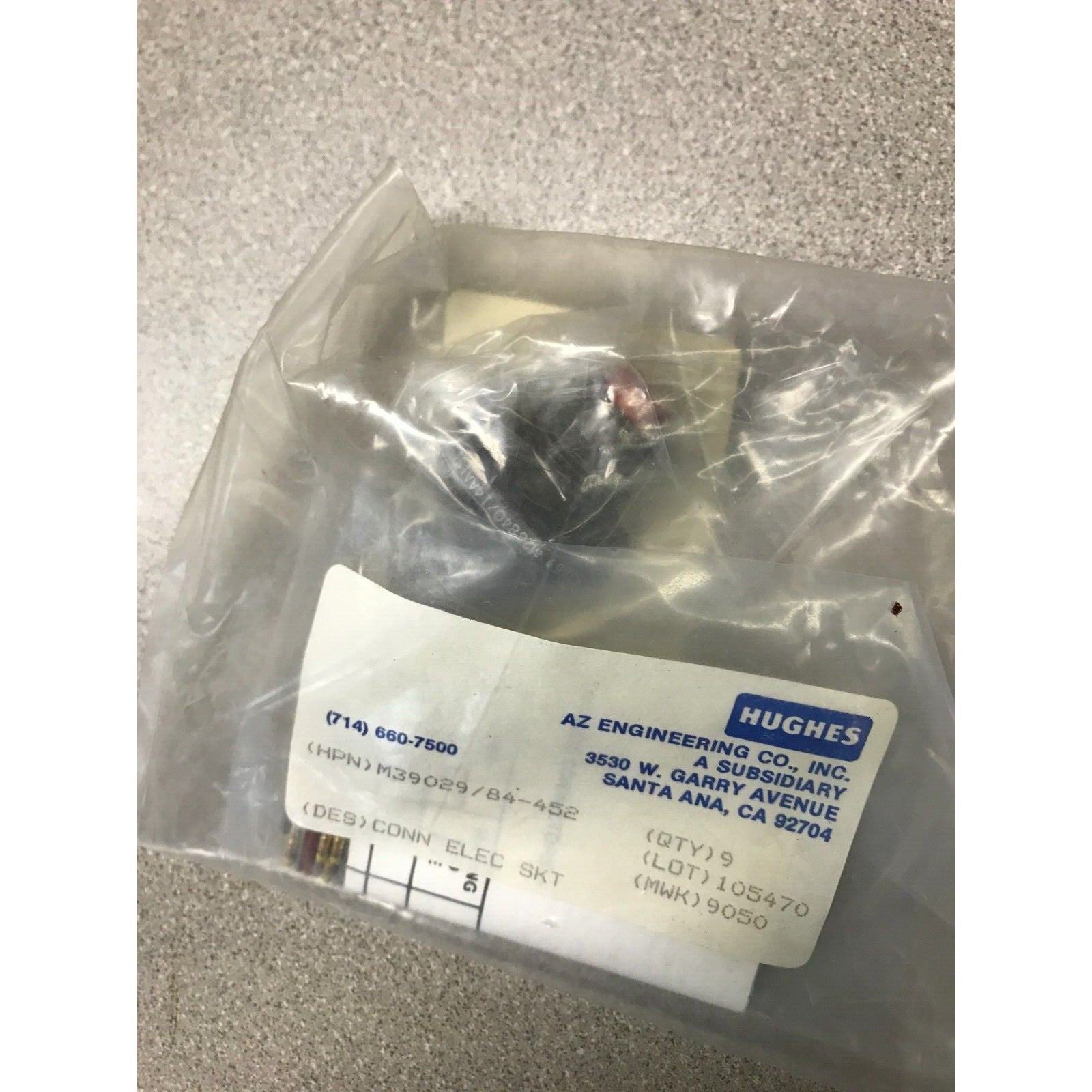 Electrical component in clear plastic packaging with a Hughes label on a gray background