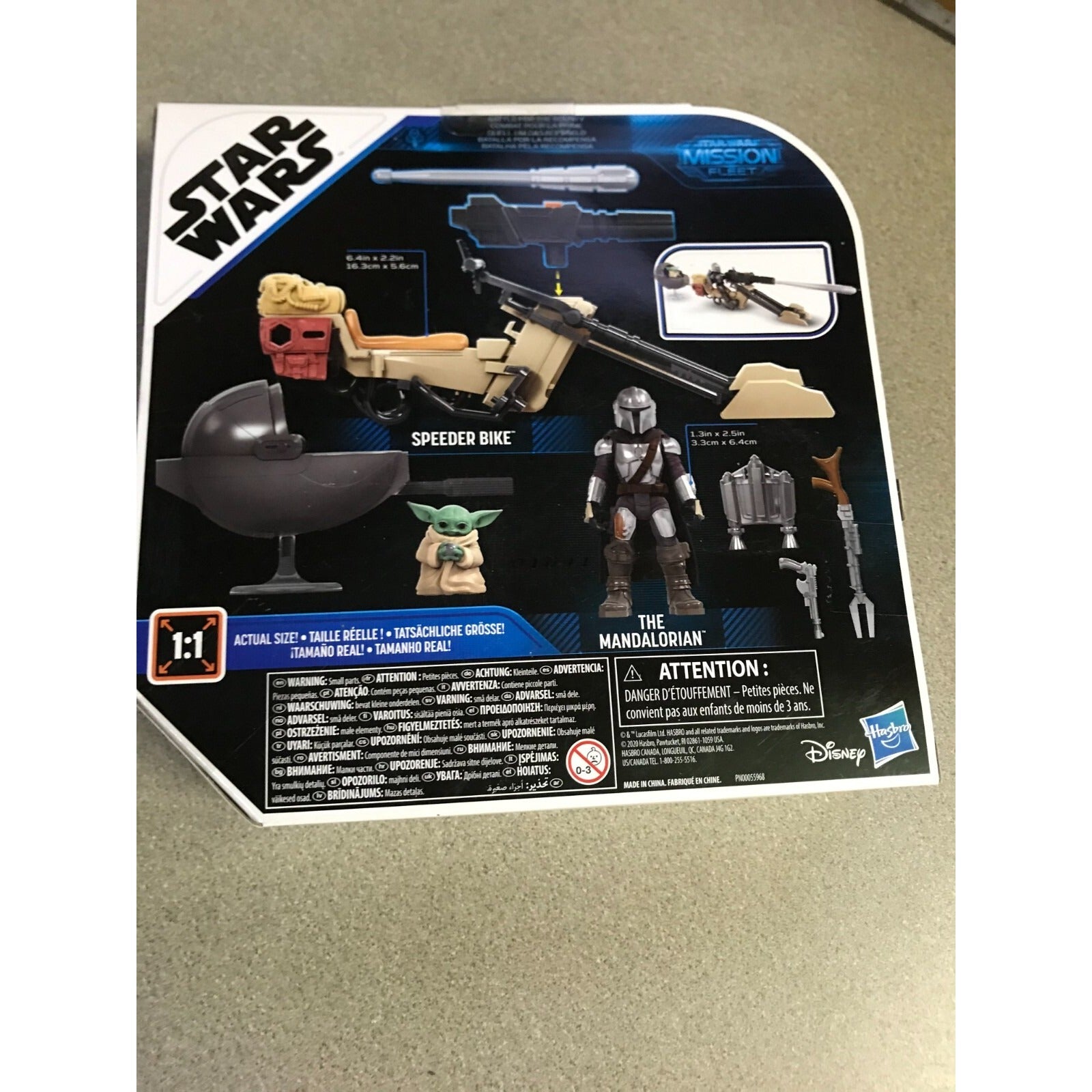 Star Wars toy packaging with figures and vehicle on a beige surface
